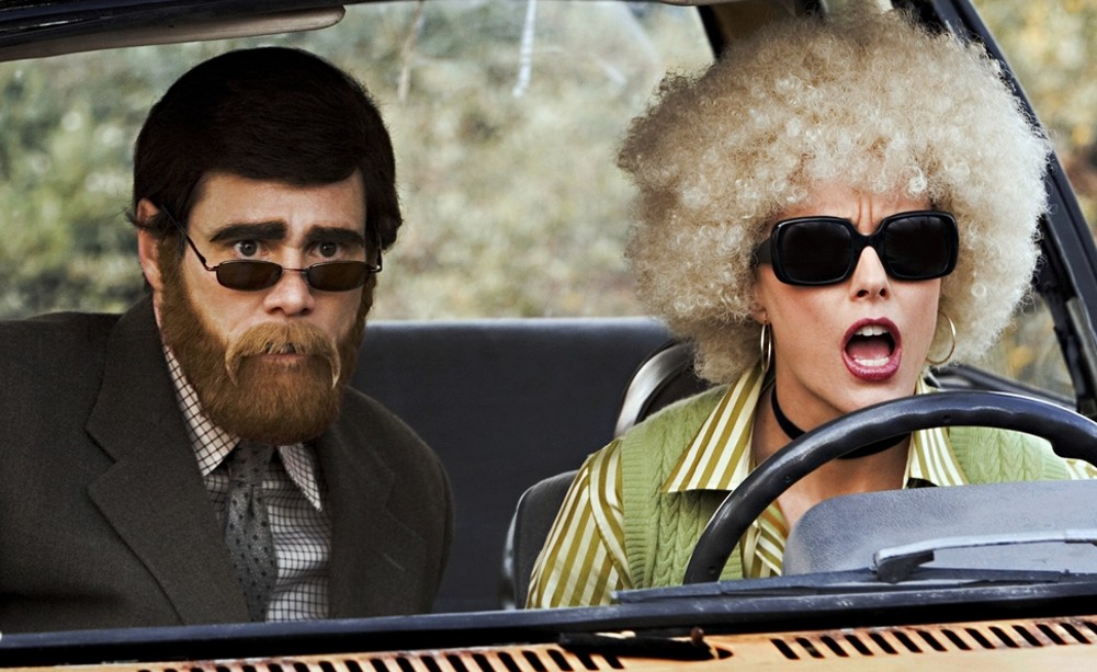 Dos personas disfrazadas se sientan detrás de un coche en Fun with Dick and Jane.
