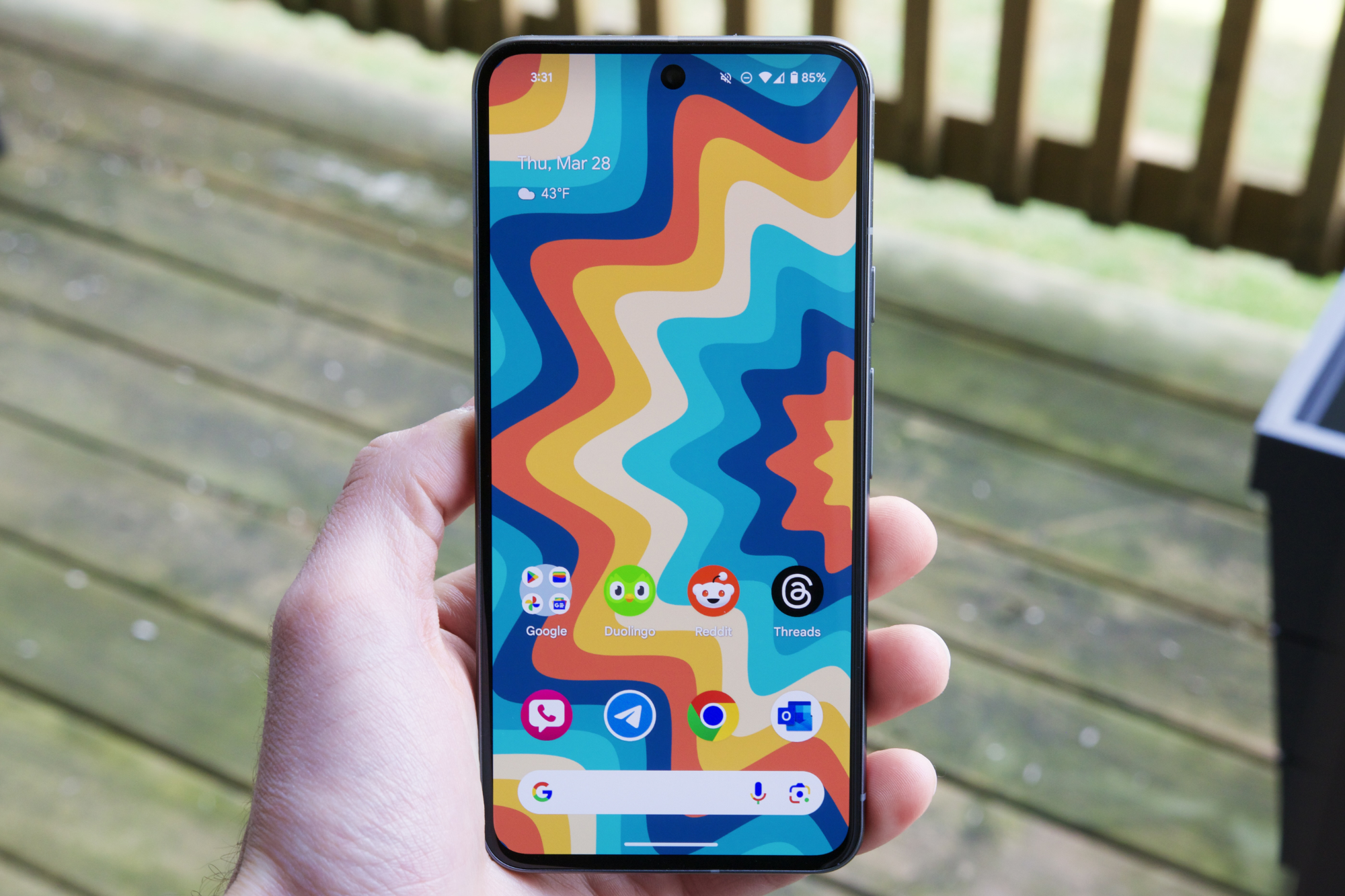 Someone holding the Google Pixel 8, showing its home screen.