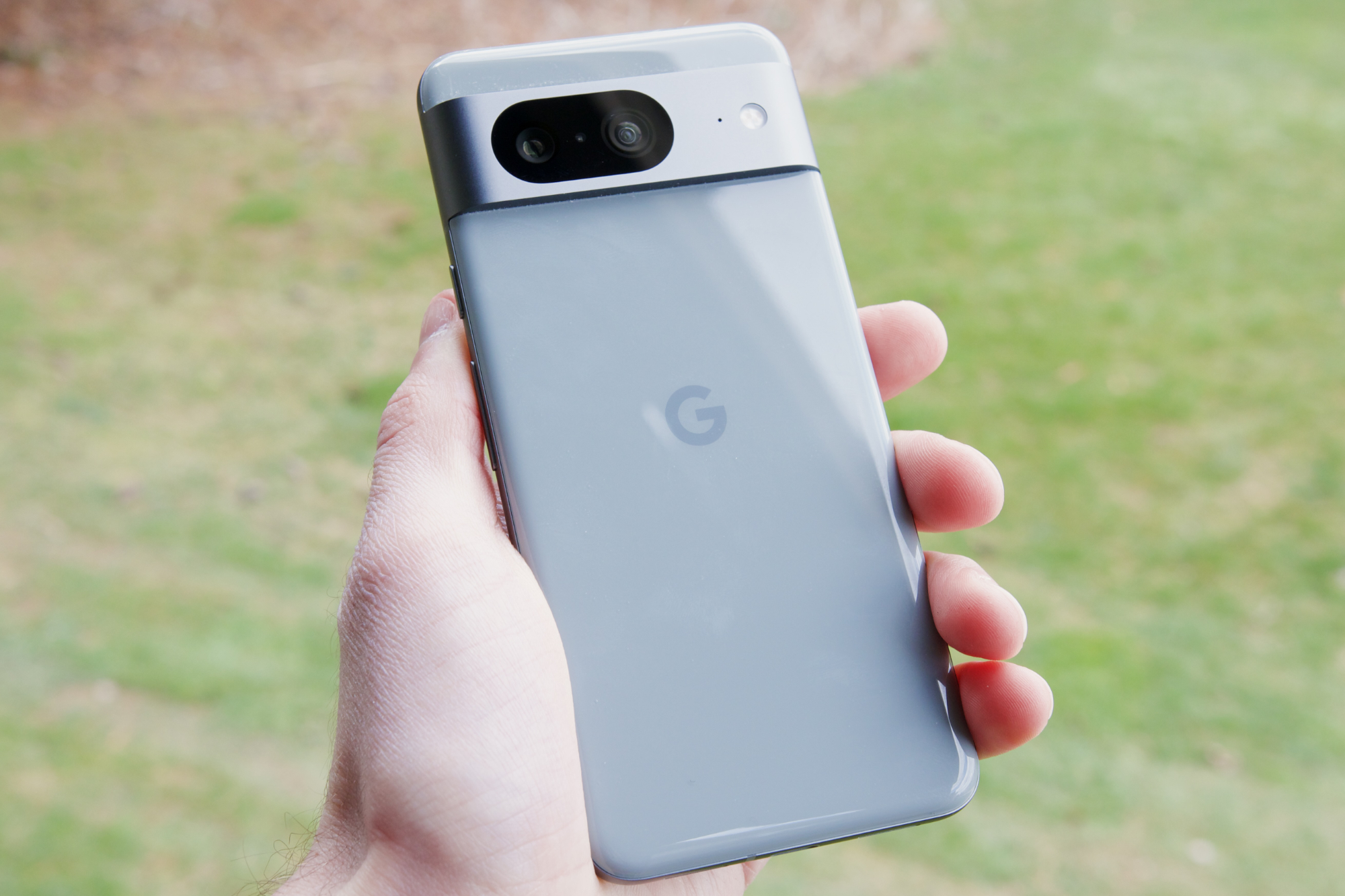 Someone holding the Google Pixel 8 outside, showing the back of the phone.