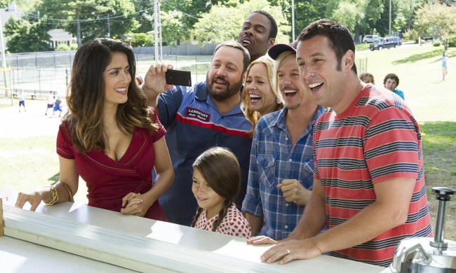 A group of men, women, and kids, including Adam Sandler and Salma Hayek standing at a counter, laughing and smiling in Grown Ups.