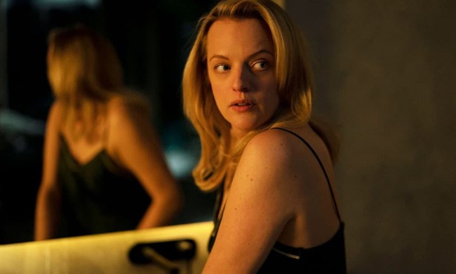Elisabeth Moss standing by a mirror, looking behind her in a scene from The Veil.