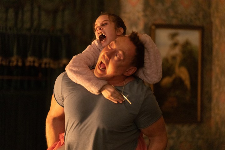 Alisha Weir hangs onto Kevin Durand in Abigail.
