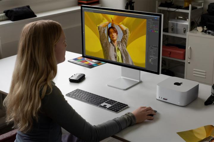 Una mujer está sentada en un escritorio con el Mac Studio M2 en él.