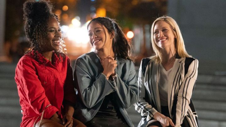 DeWanda Wise, Gina Rodriguez e Brittany Snow como Erin, Jenny e Blair sentadas na rua rindo em Alguém Ótimo.