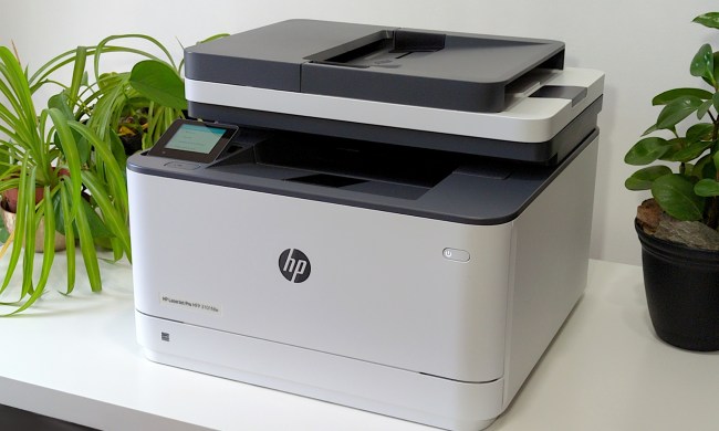HP LaserJet Pro MFP 3101fdw printer looks nice on a white stand beside plants.