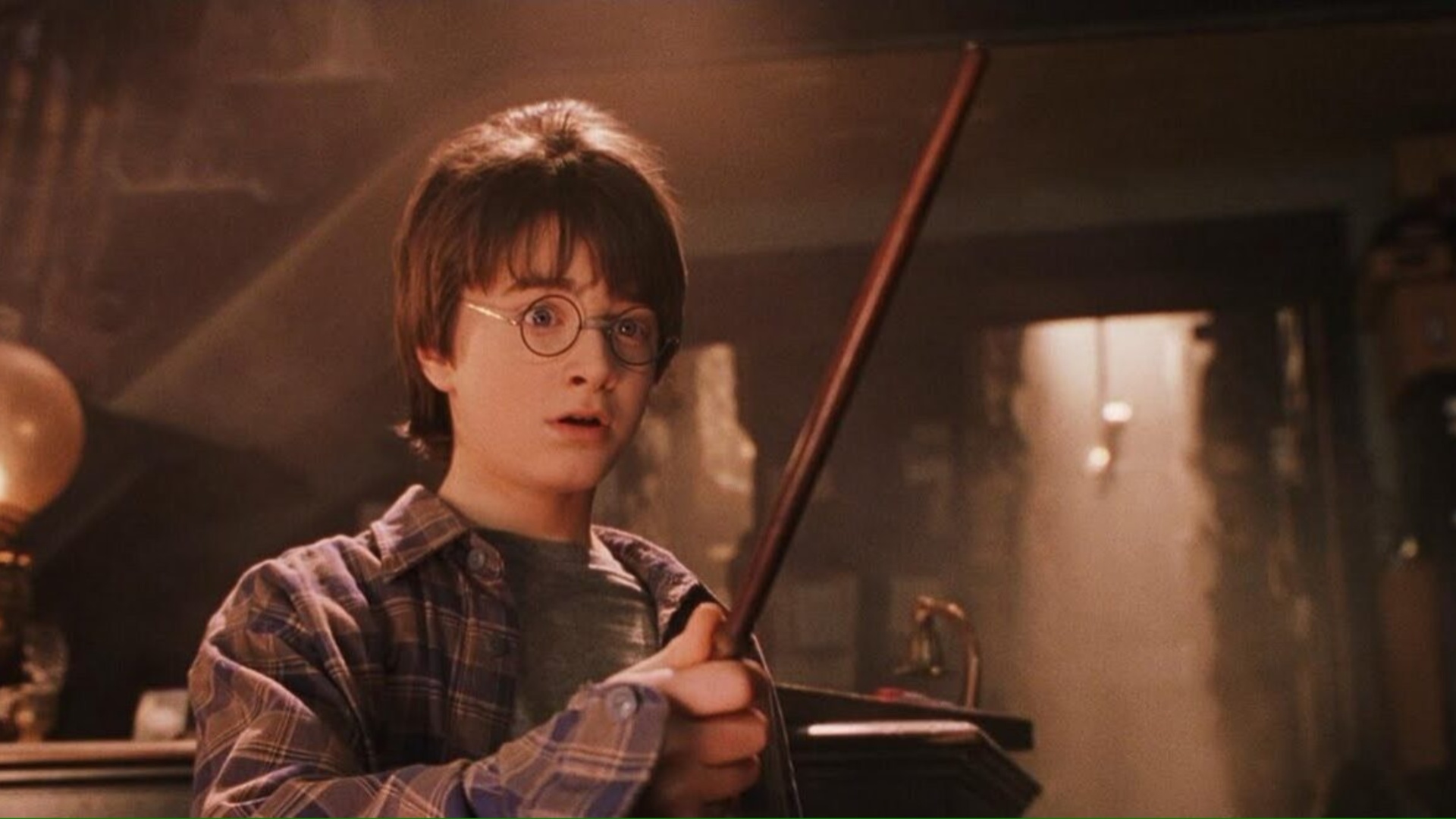 Daniel Radcliffe como Harry empuñando su varita con una expresión de sorpresa en Harry Potter y la piedra filosofal.