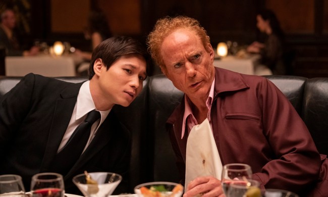 Hoa Xuande and Robert Downey Jr. sit at a dinner table together in The Sympathizer.