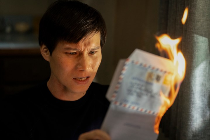 Hoa Xuande sostiene una carta ardiente en The Sympathizer.