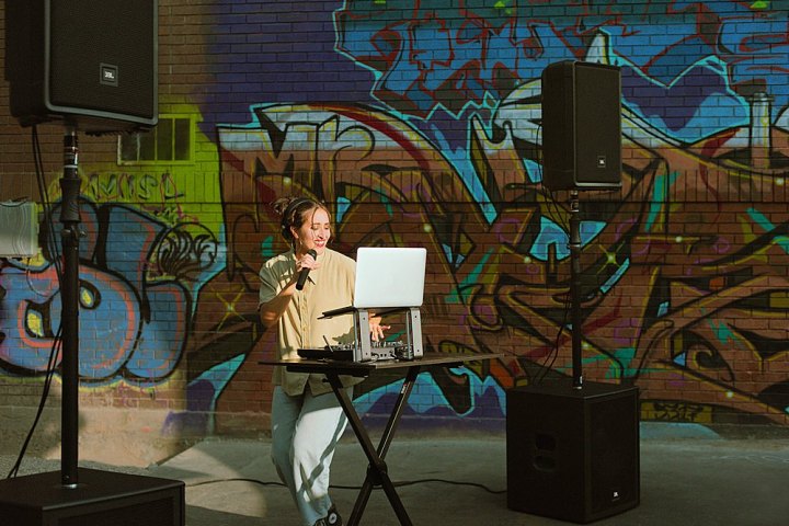 एक महिला अपने लैपटॉप और JBL IRX115S 15-इंच सबवूफर पर संगीत चला रही है।