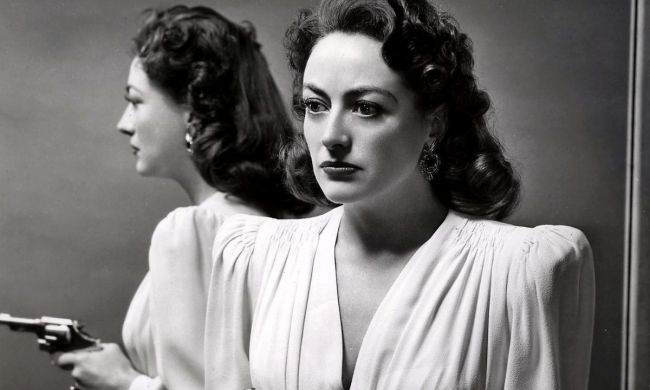 Joan Crawford as Mildred Pierce holding a gun with a mirror behind her.