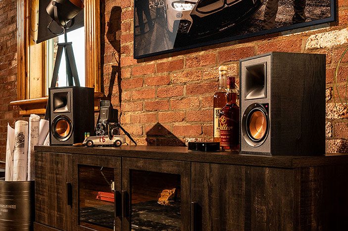 The Klipsch R-51PM bookshelf speaker placed in a wood themed living room environment.