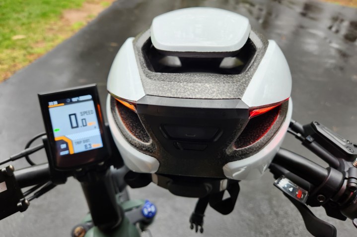 Casque Lumos Ultra lumineux reposant sur un guidon MOD Easy 3 Sidecar avec feu de signalisation gauche orange et clignotant gauche sur l'écran du vélo électrique.