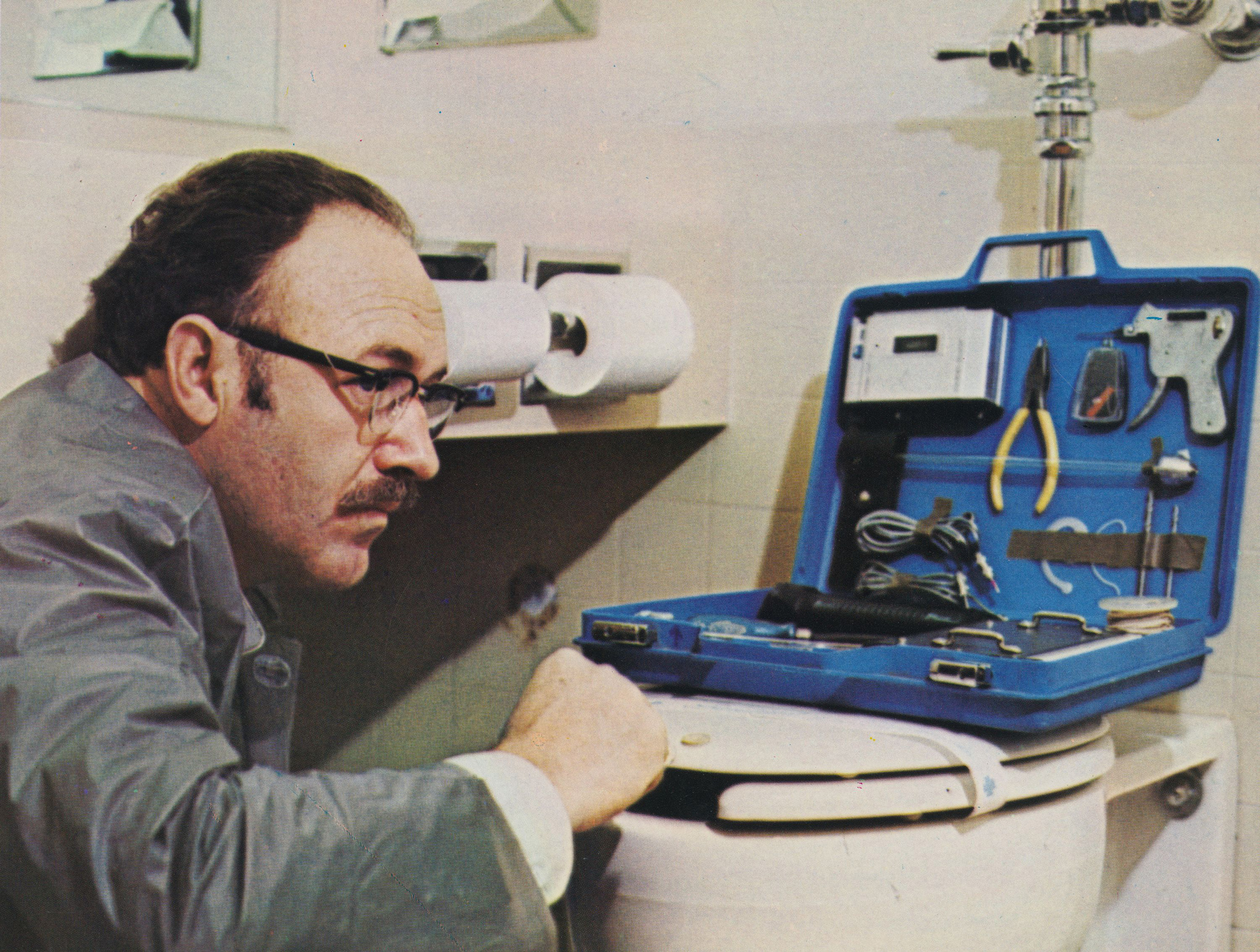 Gene Hackman abriendo una caja de herramientas encima de un inodoro en The Conversation (1974)