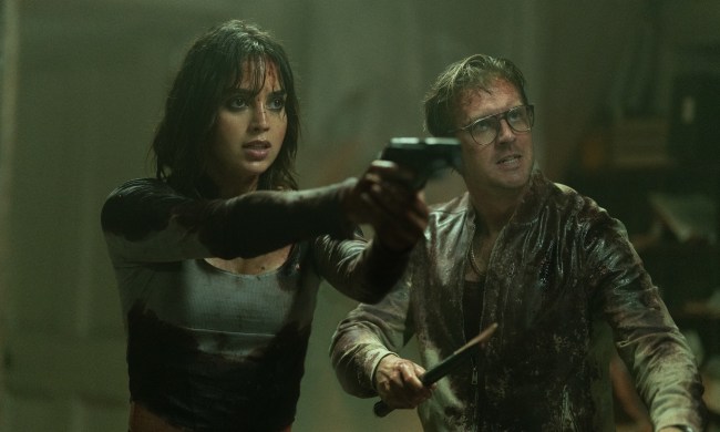 Melissa Barrera points a gun and Dan Stevens holds a wooden stake in Abigail.