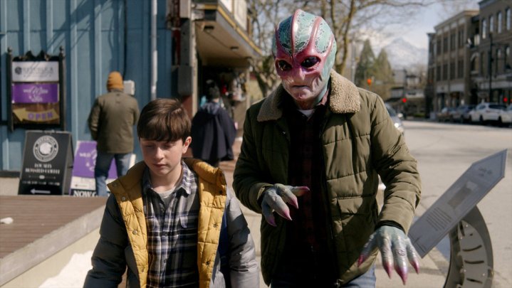 An alien and a young boy walk down the street in Resident Alien.