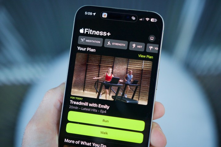 Someone holding an iPhone with the Apple Fitness app open, showing the Custom Plans feature.