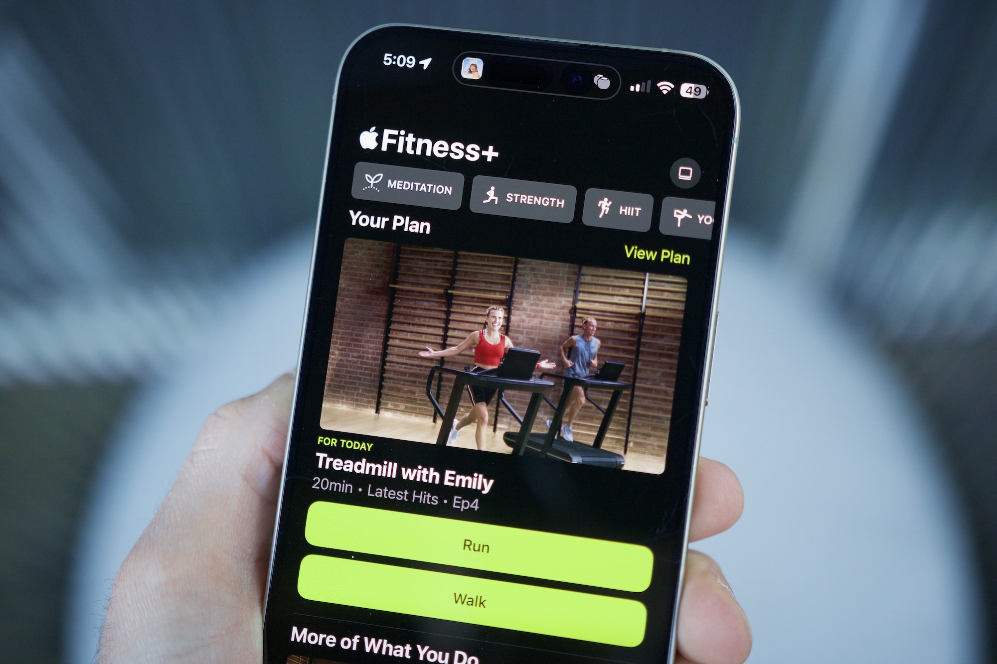 Alguien sosteniendo un iPhone con la aplicación Apple Fitness abierta, mostrando la función Planes personalizados.