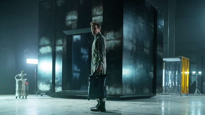 Apple TV+ पर डार्क मैटर के एक दृश्य में एक आदमी अंधेरे और सुनसान कमरे में खड़ा है।