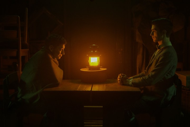 Two men sit by a lantern in Dead Boy Detectives.