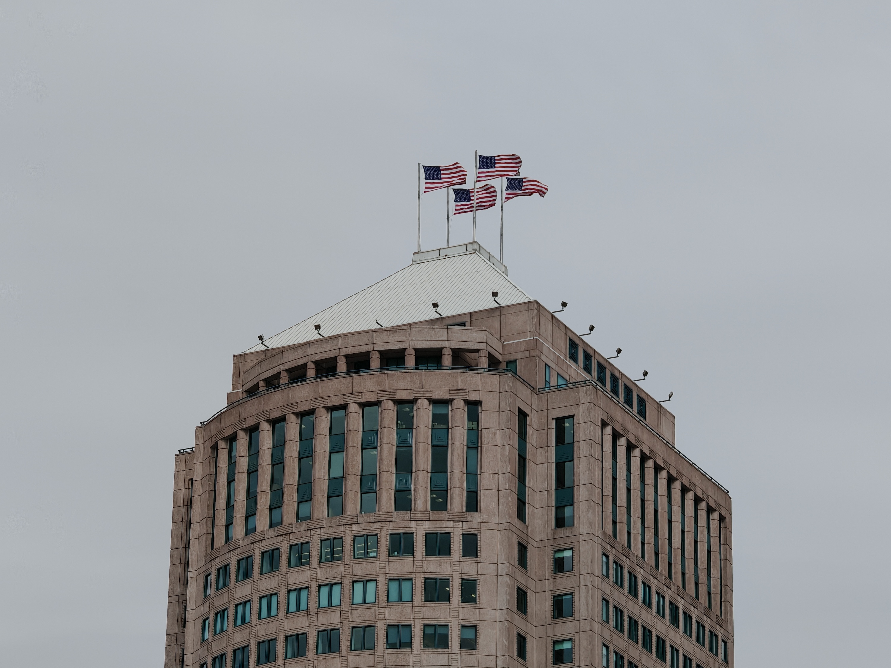 Una foto de un edificio en Detroit con cuatro banderas estadounidenses en la parte superior, tomada con el Honor Magic 6 RSR.
