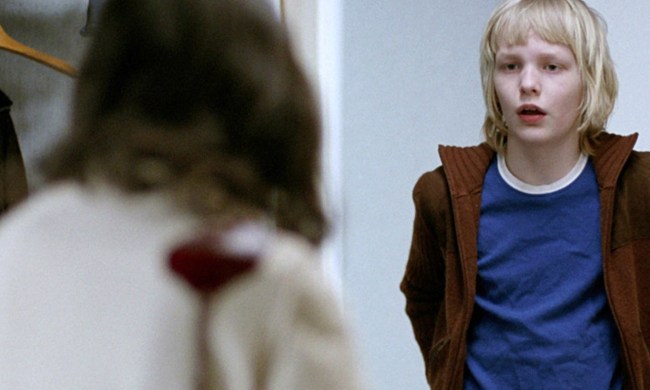 A boy looks surprised standing in front of a girl in Let the Right One In.