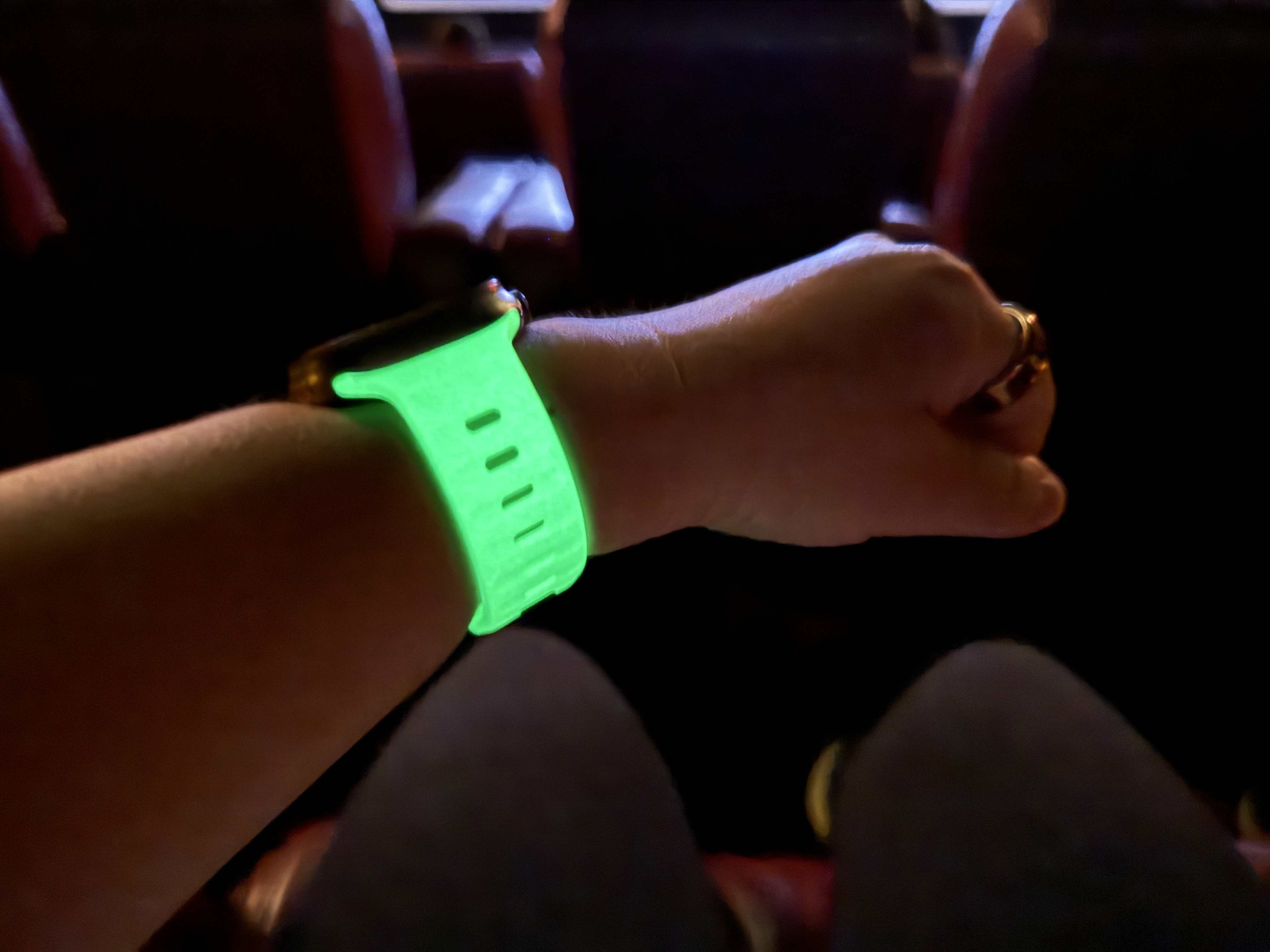 Nomad Glow 2.0 Sport Band glowing in a dark movie theater.