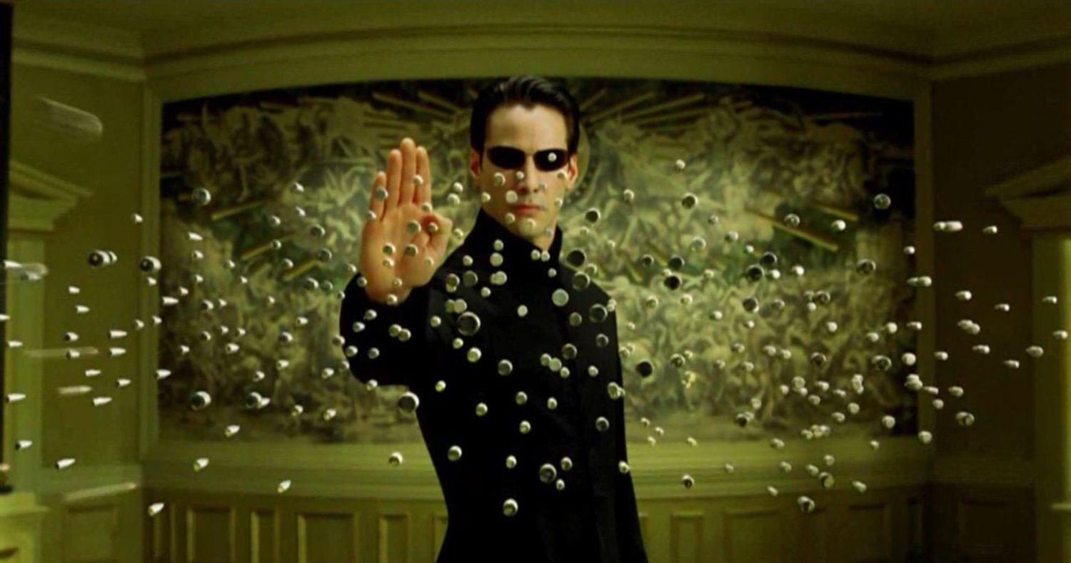 Keanu Reeves stops a hail of bullets with his mind in a still from The Matrix