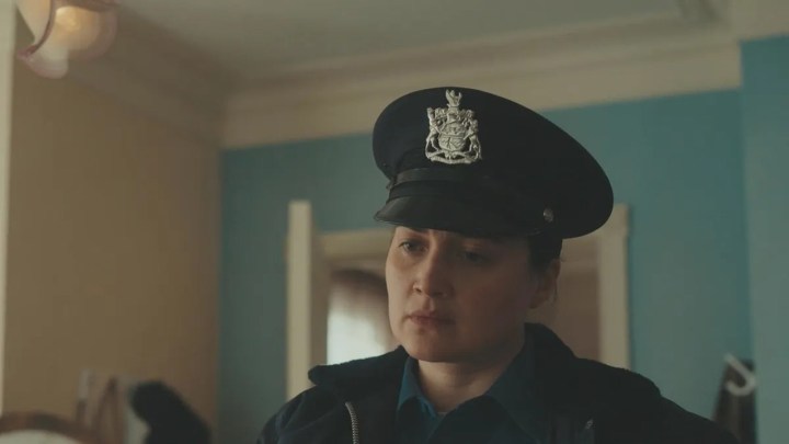 A woman in a police hat looking at someone in a scene from Under the Bridge on Hulu.