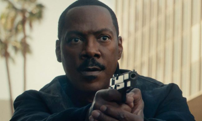 Eddie Murphy points a gun and cautiously stares.