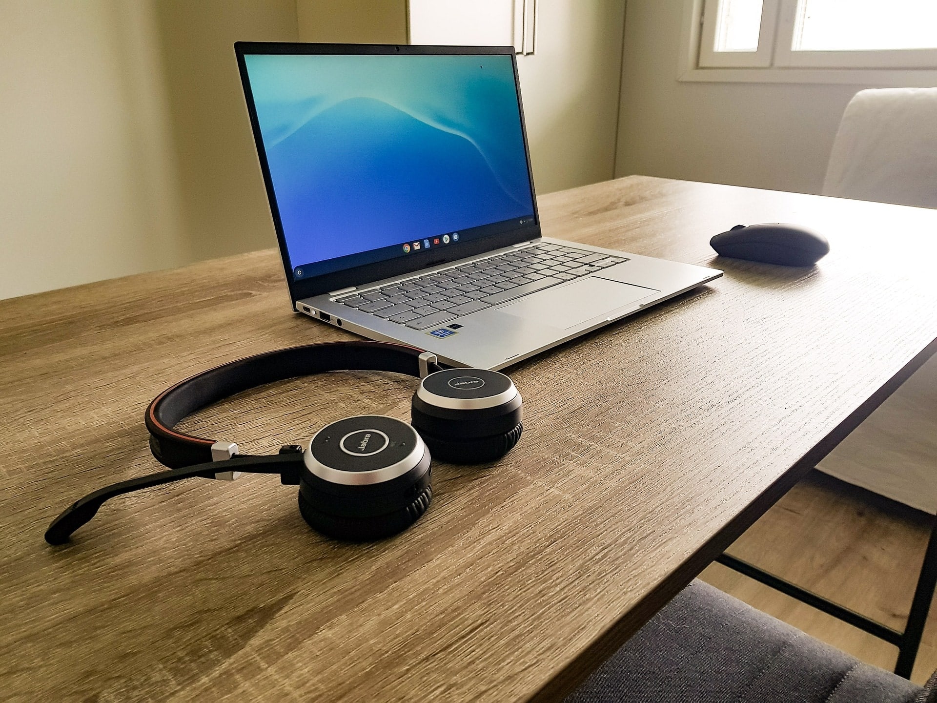Chromebook on a table with a mouse and headphones