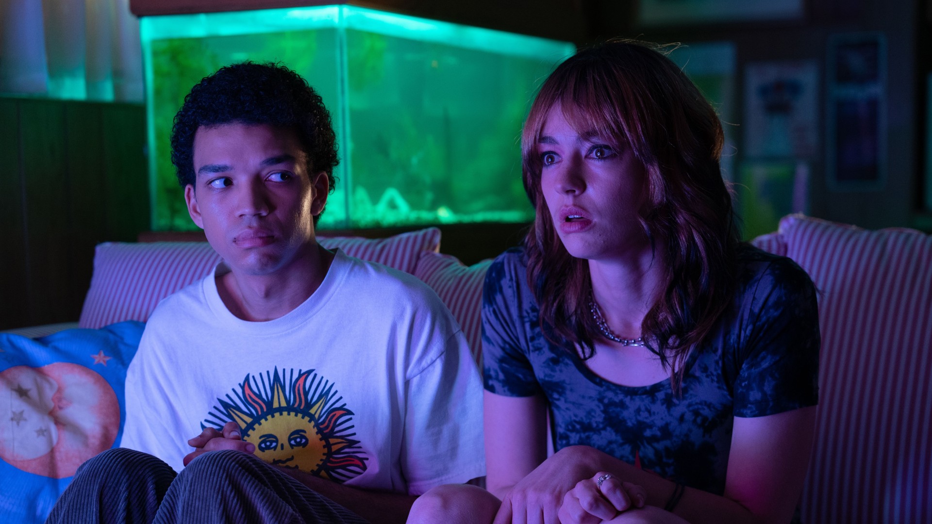 Justice Smith and Brigette Lundy-Paine watch TV with rapt attention in a screenshot from I Saw the TV Glow.