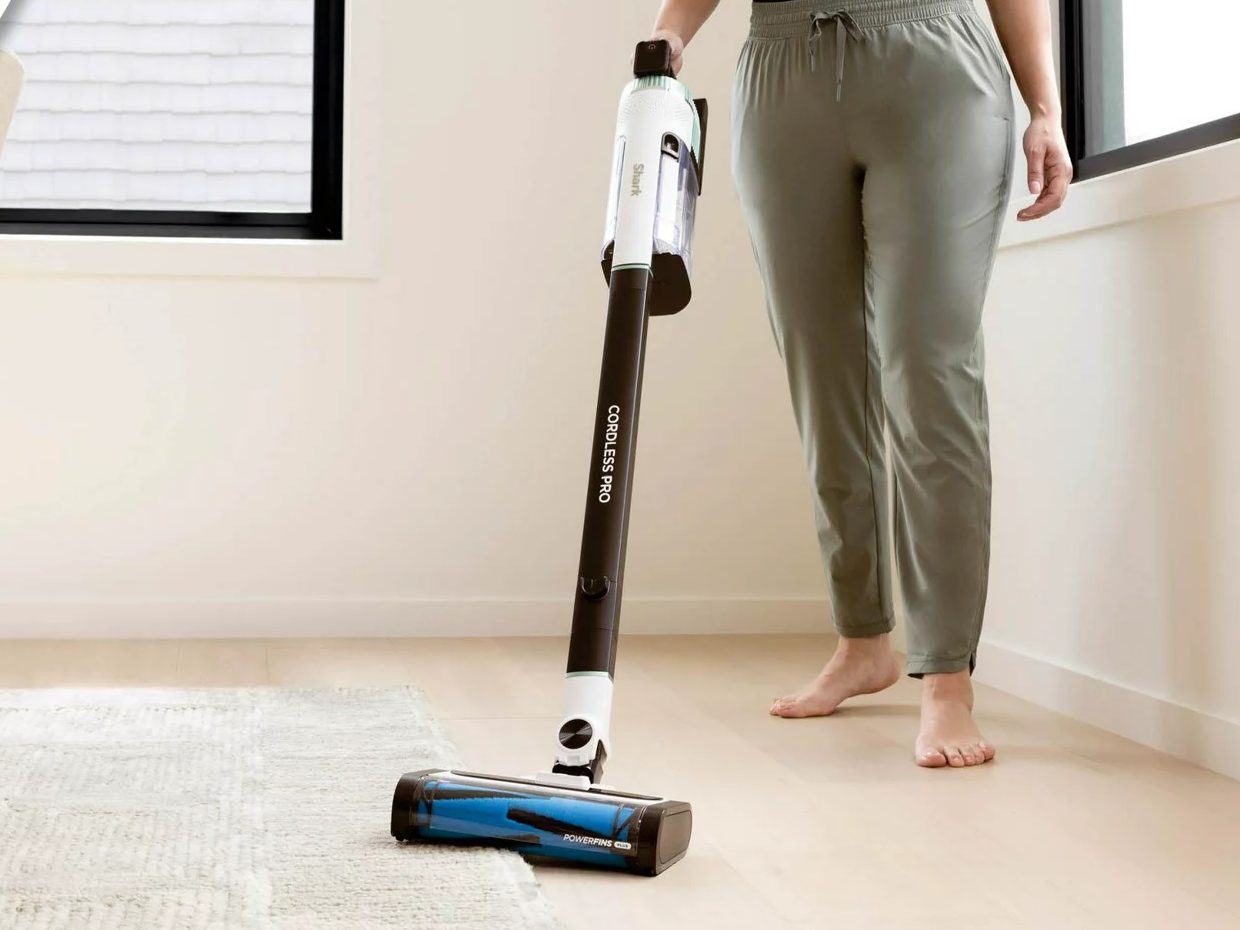 The Shark Cordless Pro Stick Vacuum being used on both carpet and hard wood flooring.