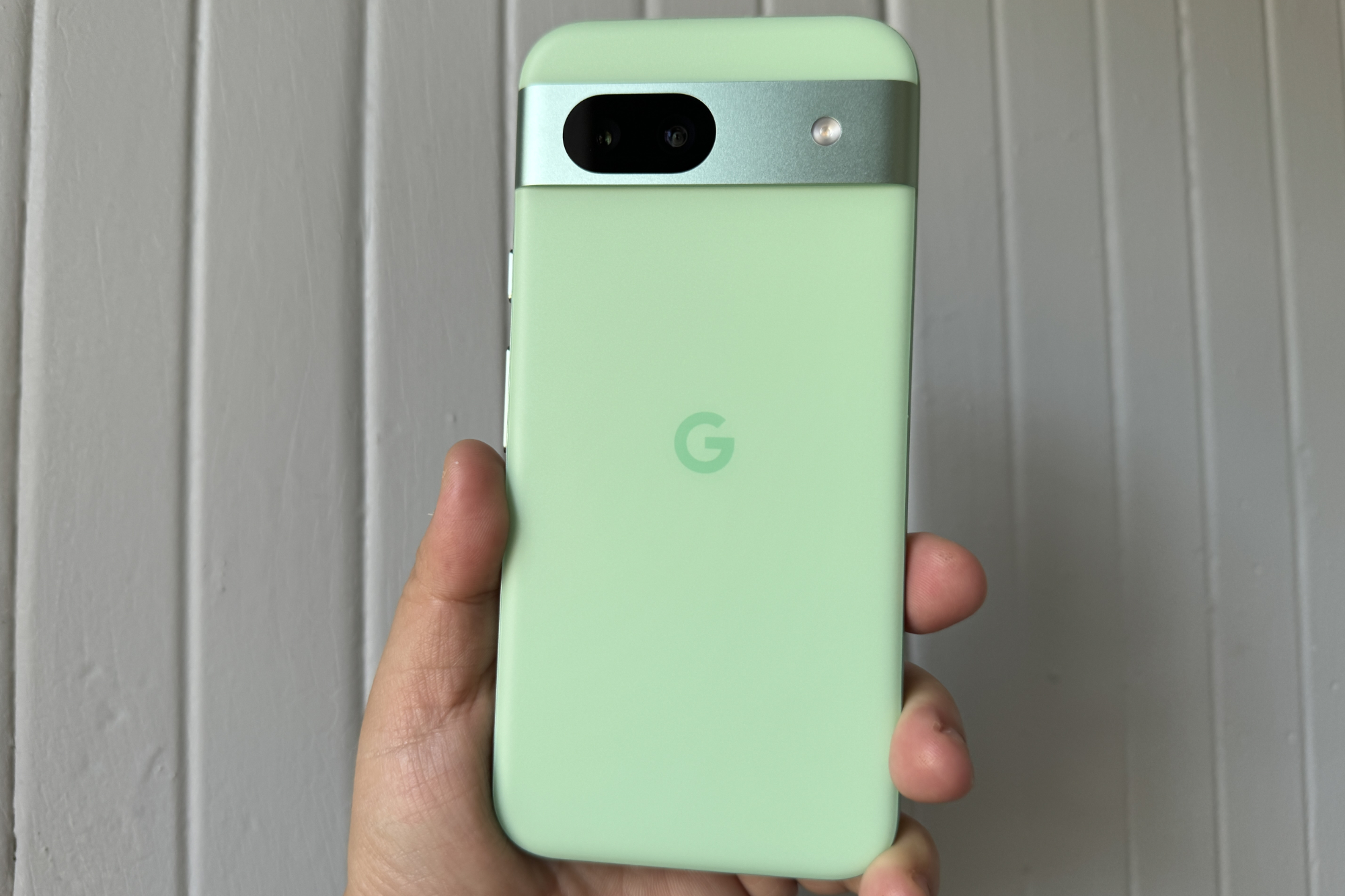 किसी के हाथ में हरा एलो Google Pixel 8a है।
