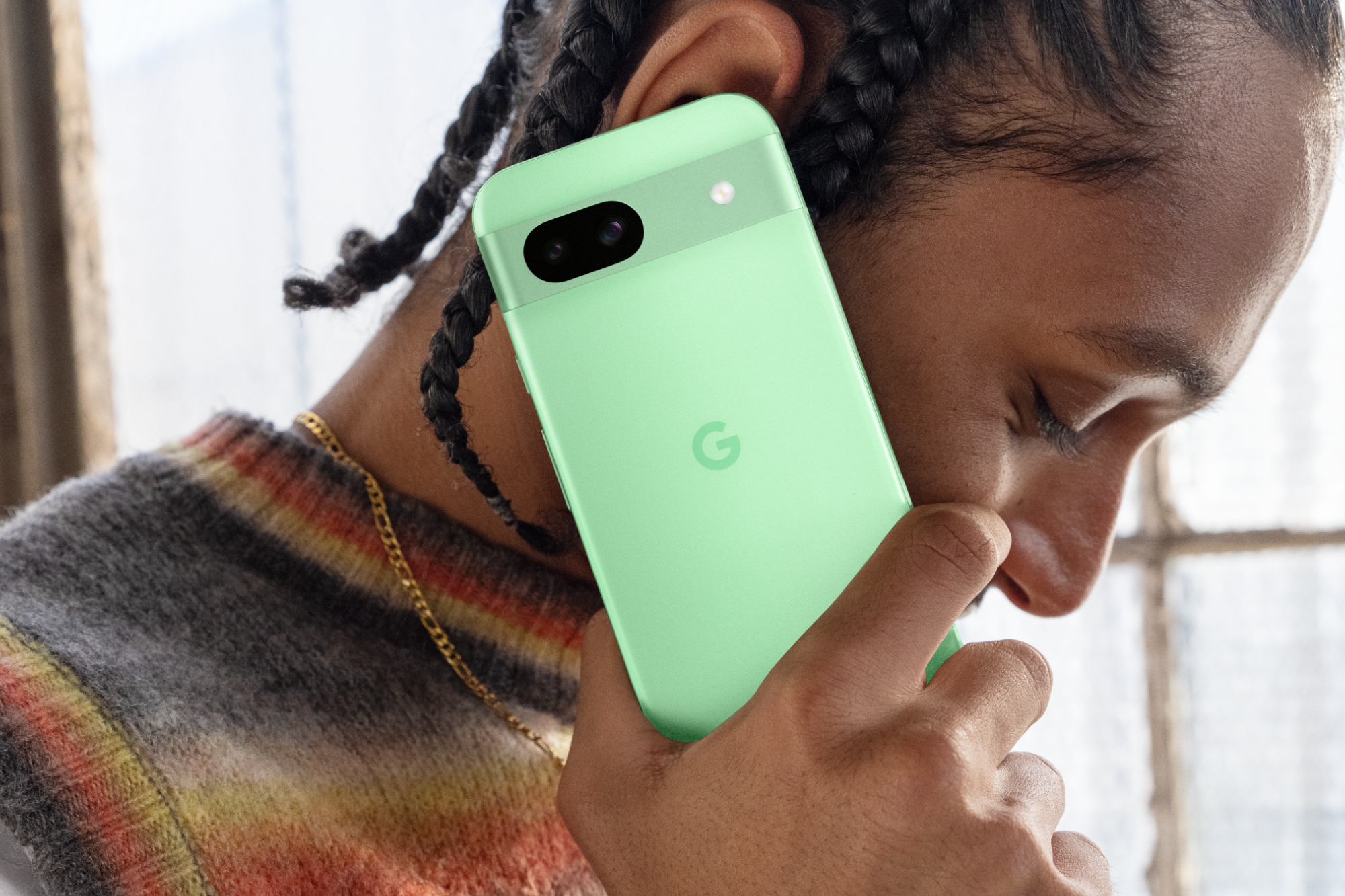 कोई व्यक्ति एलो Google Pixel 8a पर फ़ोन कॉल कर रहा है।