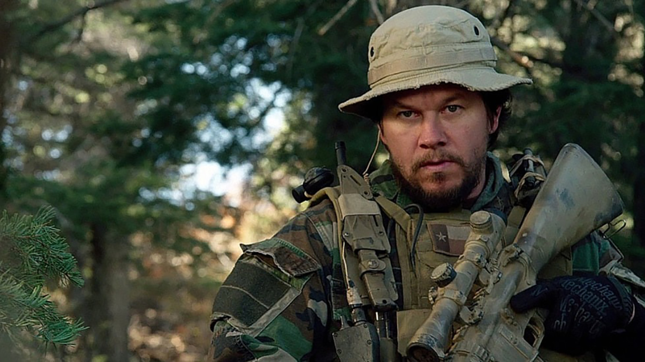 《孤独的幸存者》中马克·沃尔伯格身着军装站在森林里。