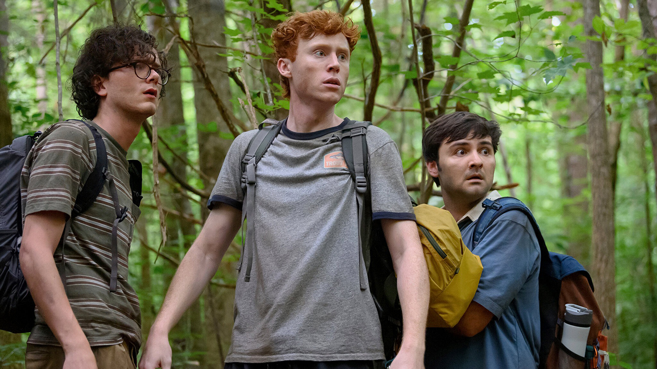 The three members of Please Don't Destroy standing in a forest looking scared in a scene from Please Don't Destroy: The Treasure of Foggy Mountain.