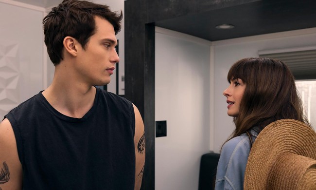 A young man in a tank top and a woman walking opposite directions stop to look at one another in a scene from The Idea of You.