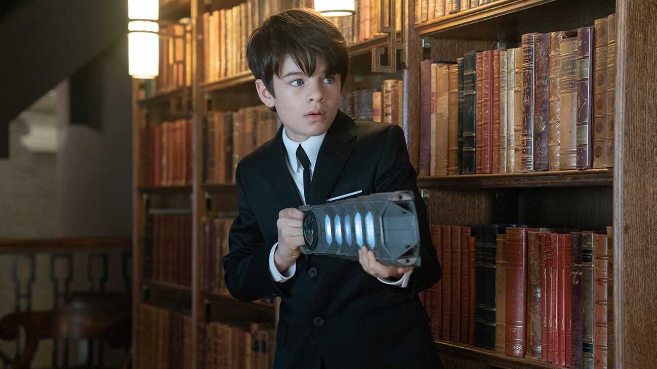 Artemis Fowl apuntando con un arma a algo fuera de cámara en Artemis Fowl.